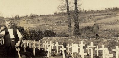 A man stands near grave markers.