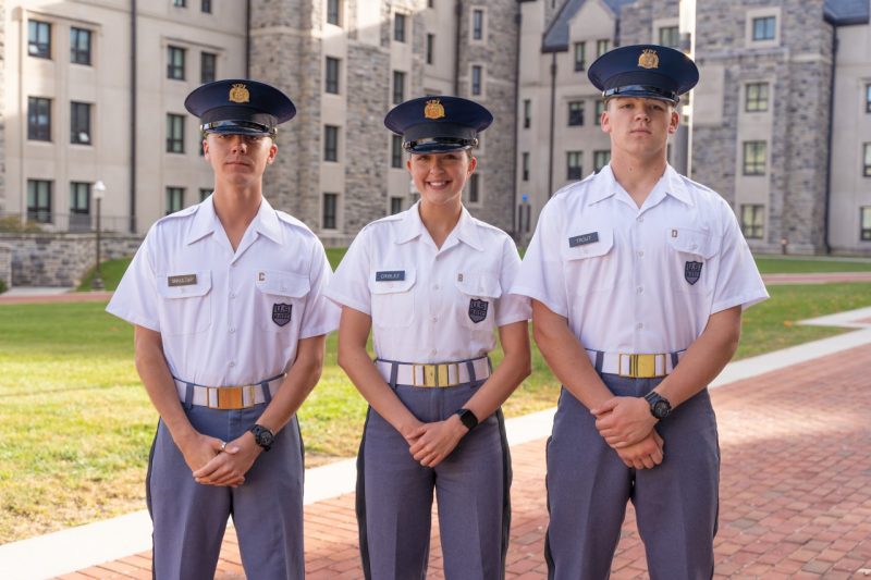 Cadets in uniform stand smiling on Upper Quad. 