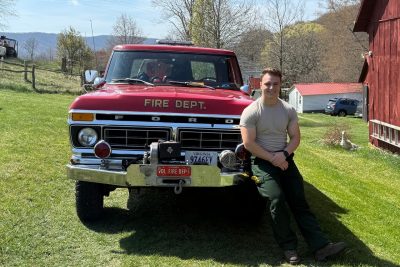 Danny Wells sits on the front fender of a fire department truck.