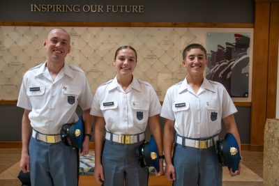 Cadets in uniform stand smiling in the atrium of a building. 