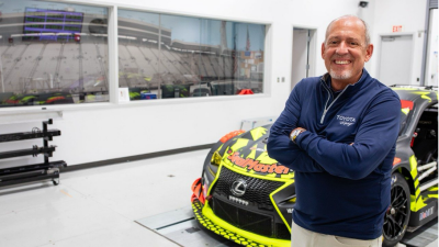 David Wilson stands in front of race car at Nascar facility 