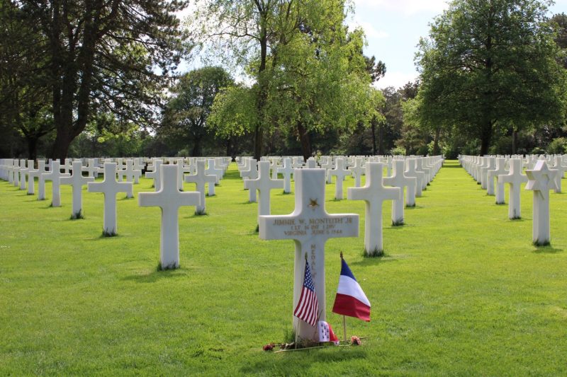 White cross headstone of Jimmie Monteith at Normandy cemetery. Other US servicemen graves fill the background.