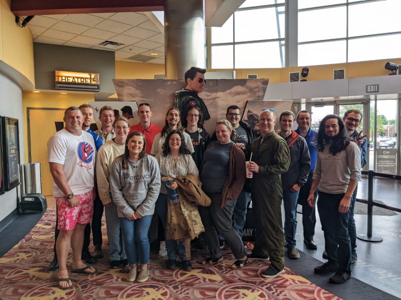 A group of people stand smiling for the camera inside a movie theater lobby
