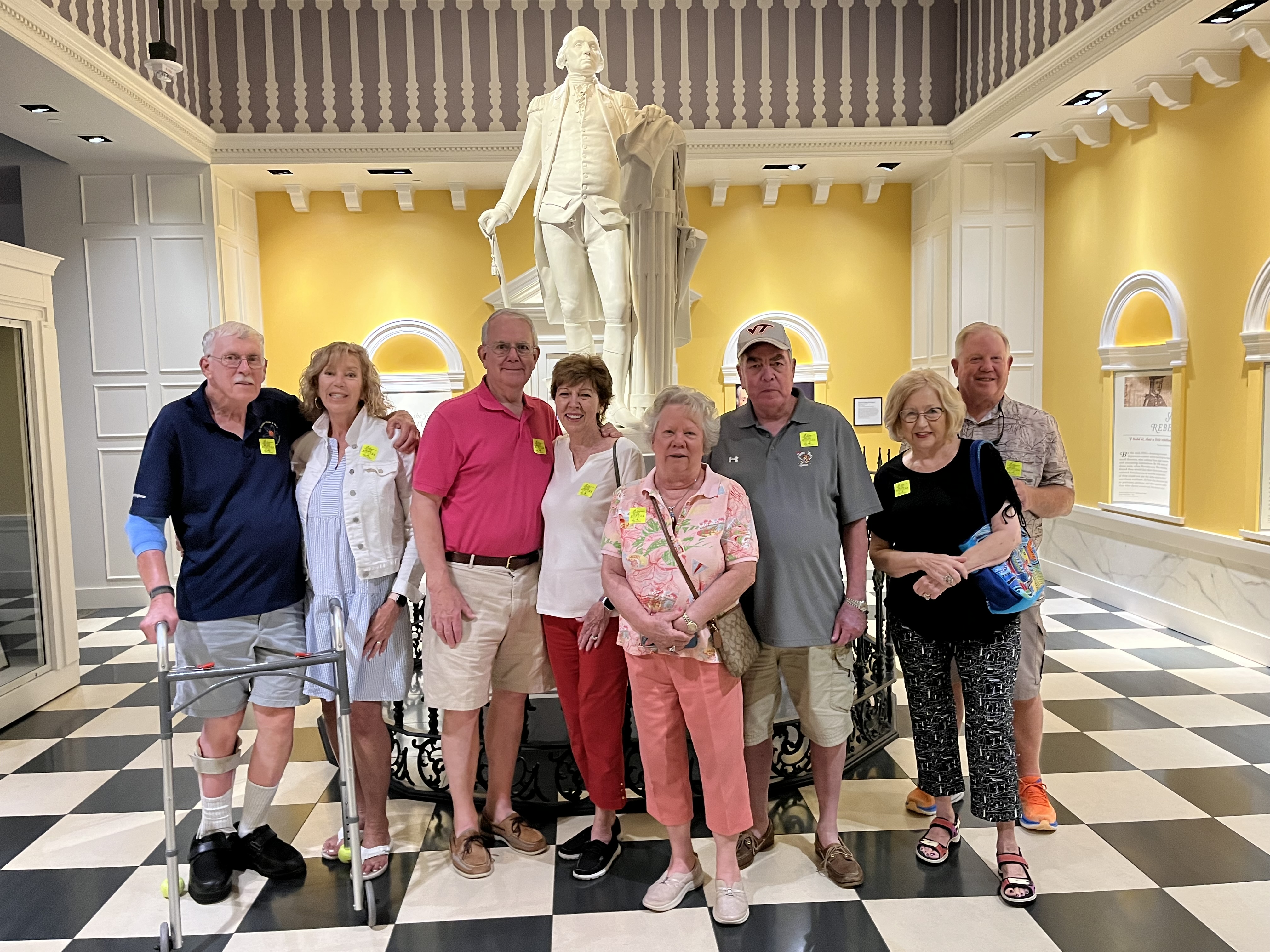 The group stands in front of a white statue in an ornate yellow room