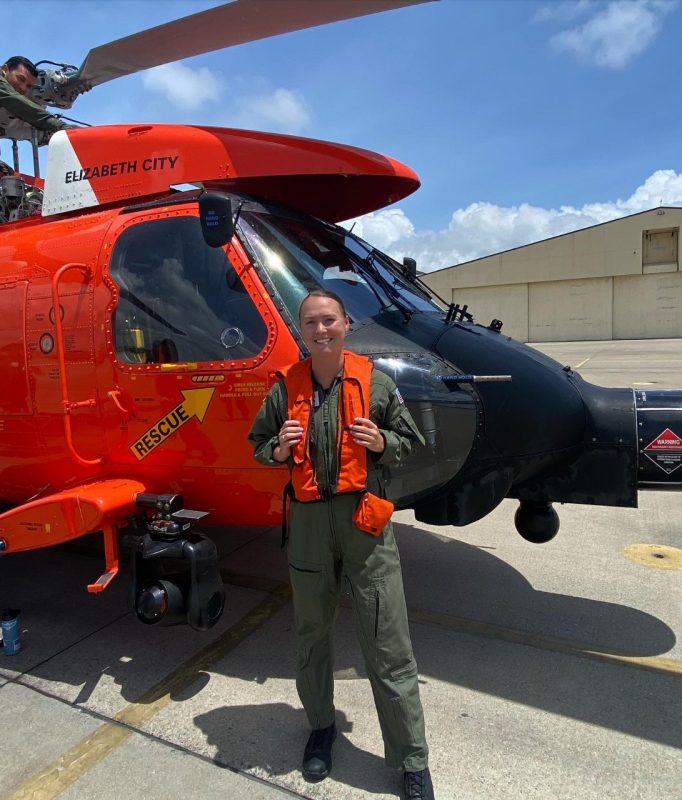 Cadet Payton Hancock, a member of the Citizen-Leader Track, stands with a Coast Guard rescue helicopter during training with the Coast Guard Auxiliary University Program.