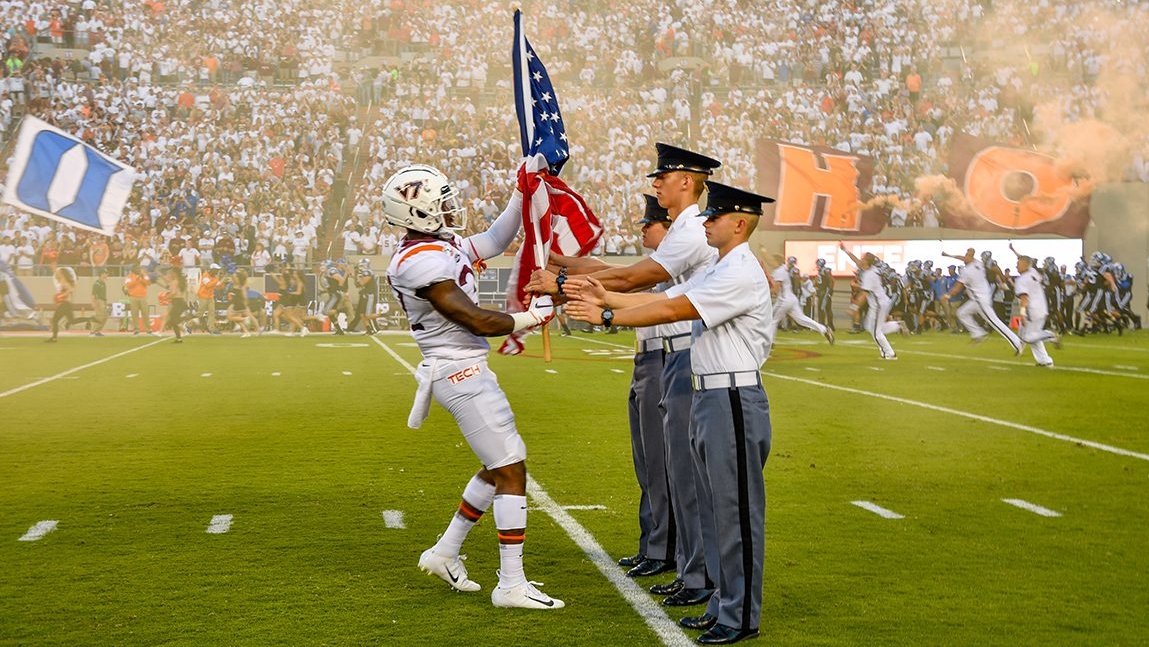 Cadets receive the flags from a football player in Lane Stadium.