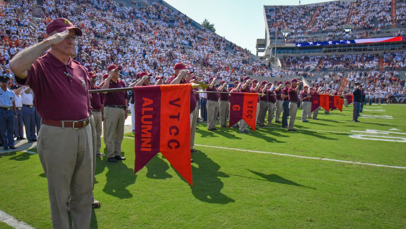 Alumni stand on Worsham Field and salute during the national anthem.