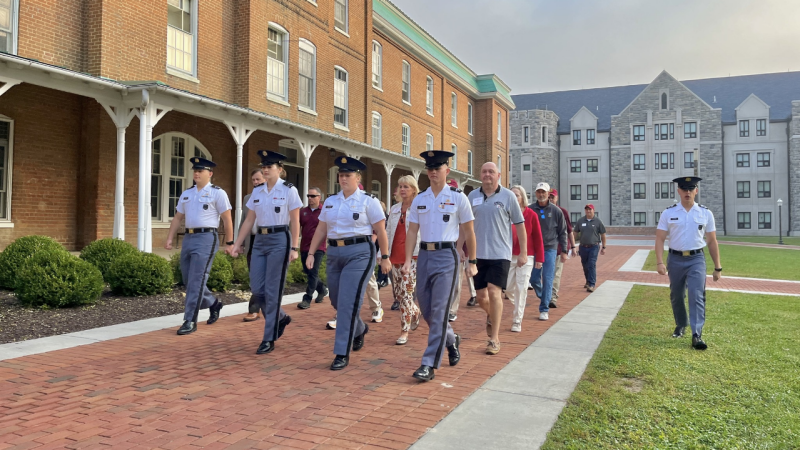 Cadets lead a formation of alumni marching in front of Lane Hall on a foggy morning.