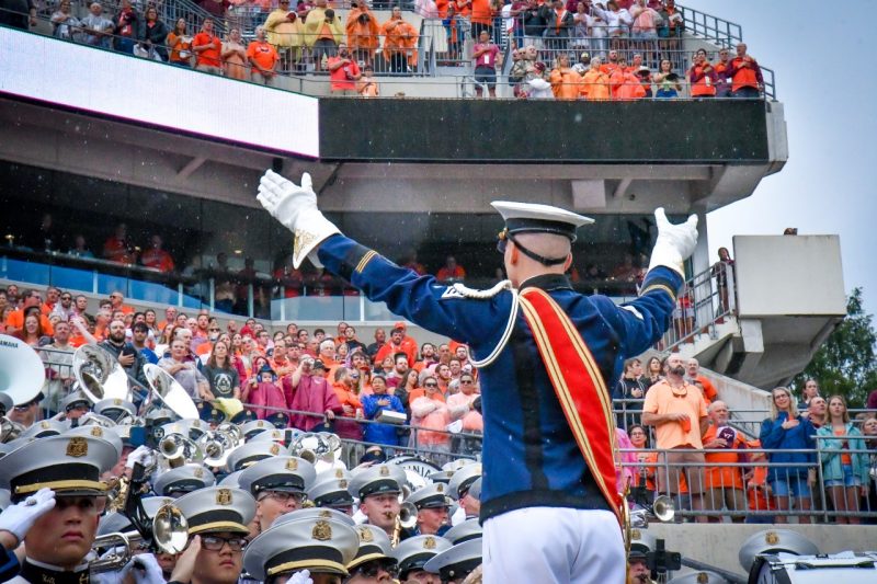 The drum major faces the band and conducts while cadets around him salute during the national anthem.