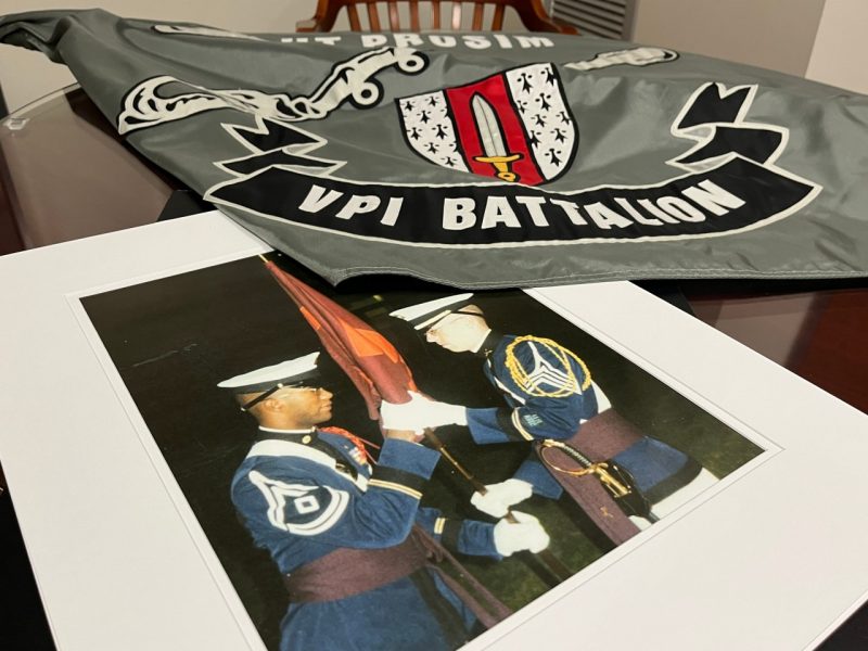 Matted photo of the VPI activation ceremony with (then) Cadet Ernest Cage receiving the company guidon, and the VPI Battalion flag in use today. 