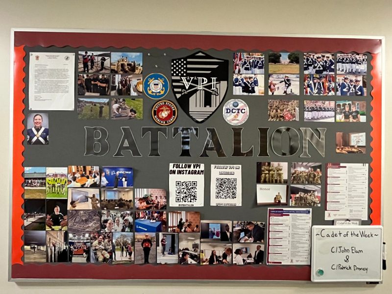 Bulletin board with the a sticker and large words reading "VPI Battalion". There are many photos, memos, and a small board for Cadet of the Week.
