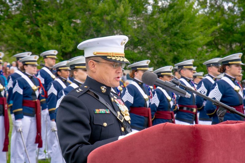 Maj. Gen. Seely speaks at a podium in his dress uniform as cadets stand in dress uniforms behind him on the Drillfield
