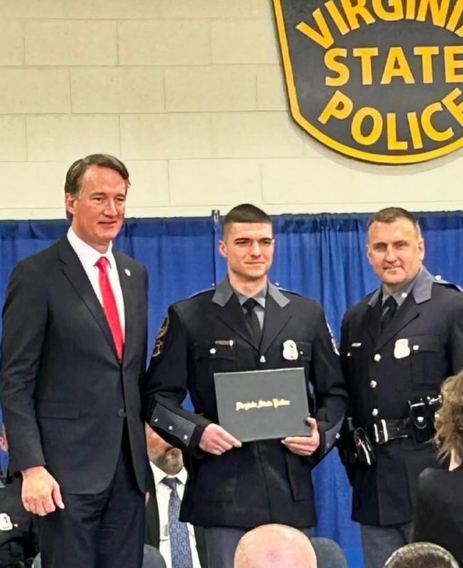 Zandipour holds a certificate and stands with the governor and a police officer