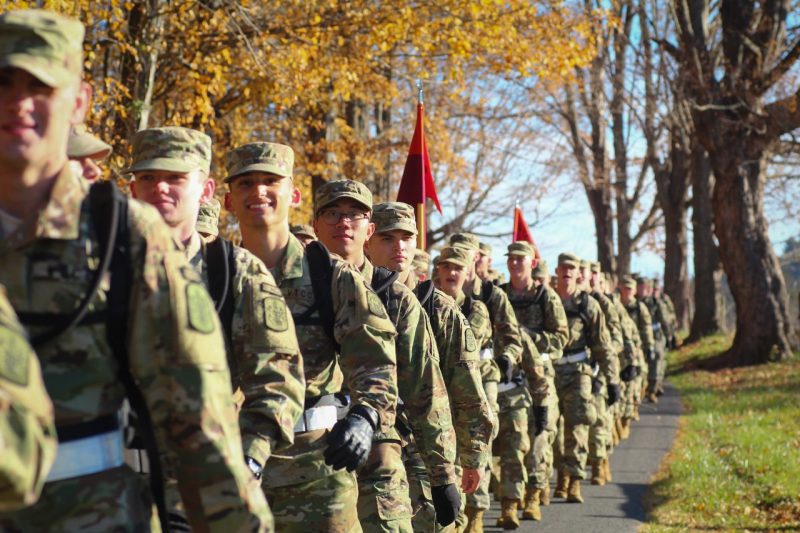 Cadets walk in a long line with fall foliage in the background