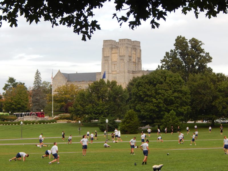 Air Force cadets do PT on the Drillfield with Burruss Hall in the background.