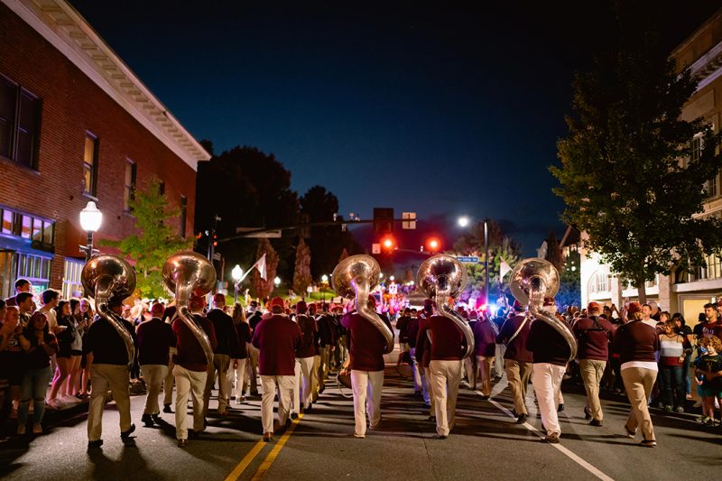 Alumni are seen from behind marching through downtown Blacksburg.