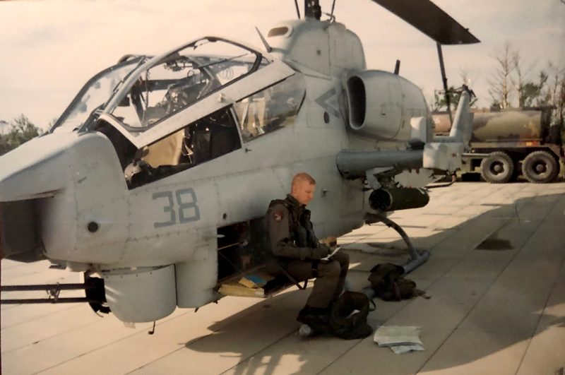 Borella sits in a chair next to a Marine Corps AH-1W Cobra.