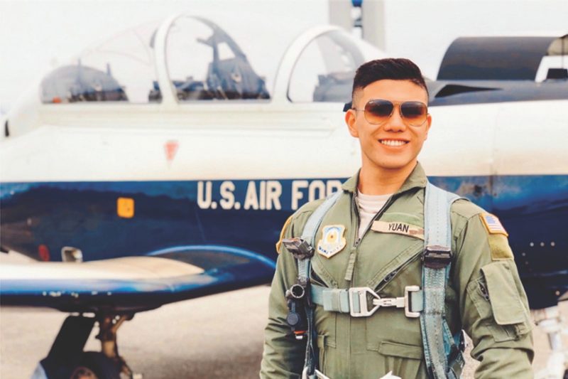 An Air Force ROTC cadet poses in front of an aircraft.