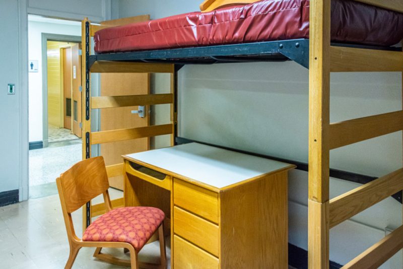 The room contains a lofted bed over a desk with a chair.